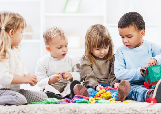Brincar com os filhos. 4 crianças brincando com alguns brinquedos enquanto estão sentados no chão
